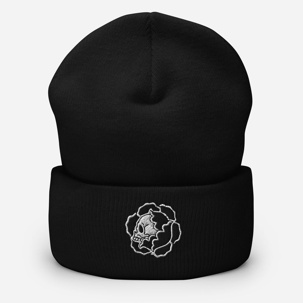 Black beanie with a white embroidered traditional skull design on a light gray background