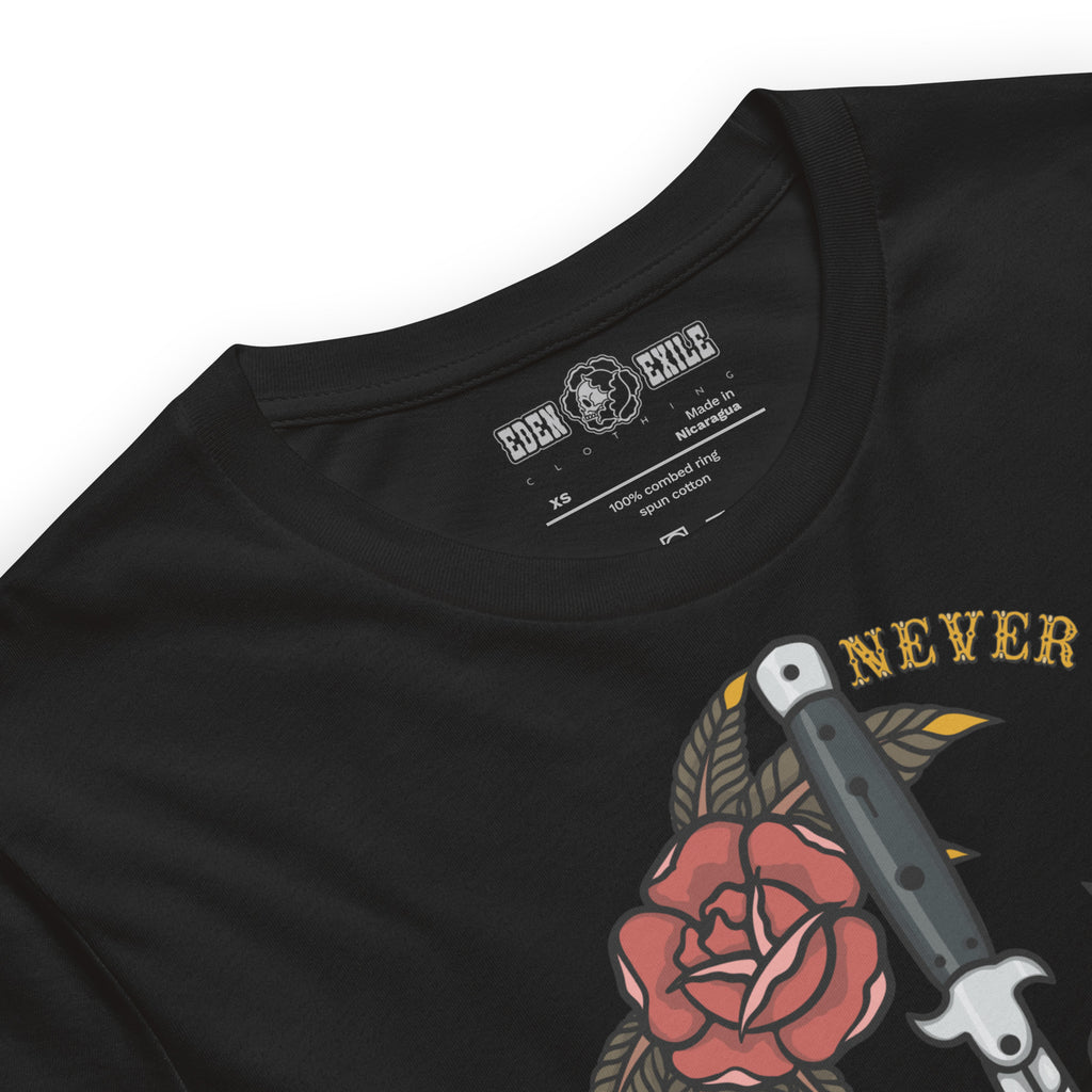 Close-up of a black short-sleeve t-shirt showing the inner neck label with 'EDEN EXILE' branding and part of the graphic print featuring a red roses, a knife, and the word 'NEVER say die' in gold.
