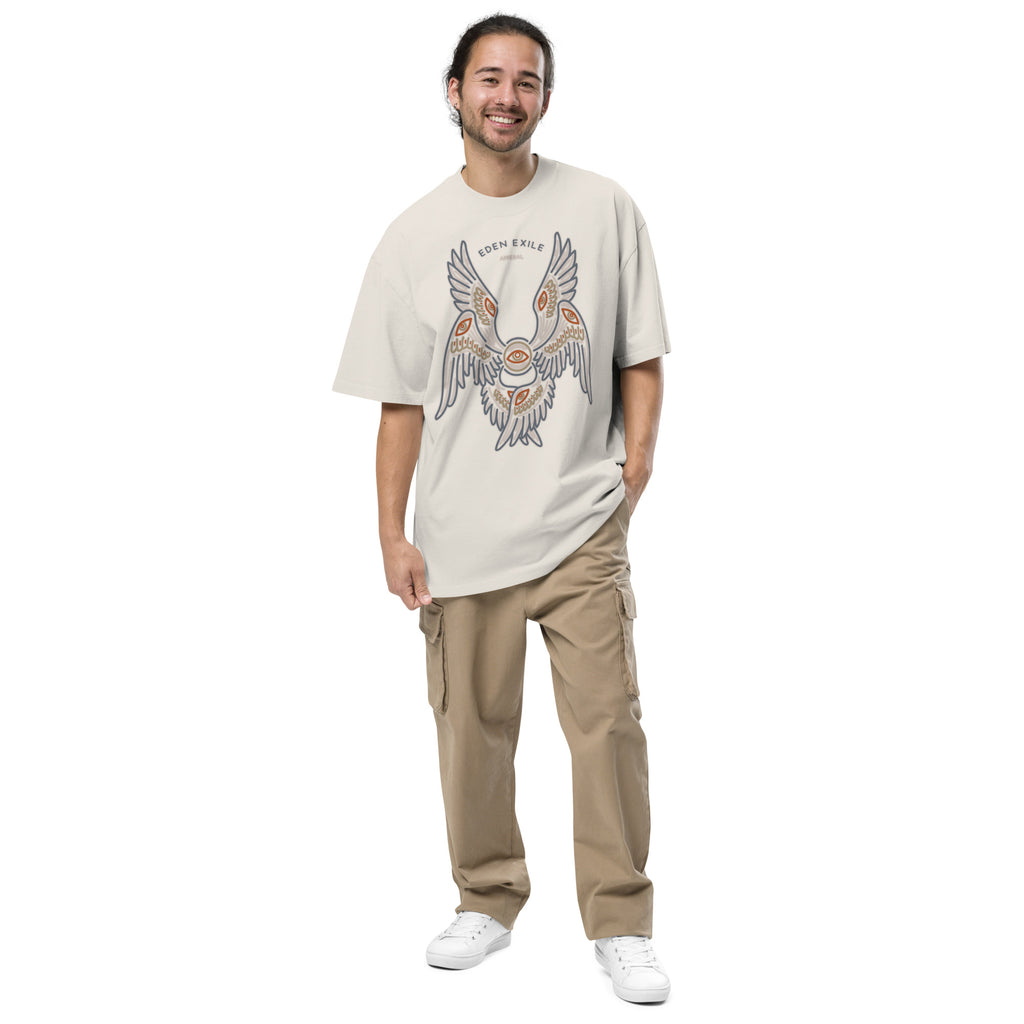 Man wearing a beige t-shirt with a angel graphic design, standing next to a vehicle.