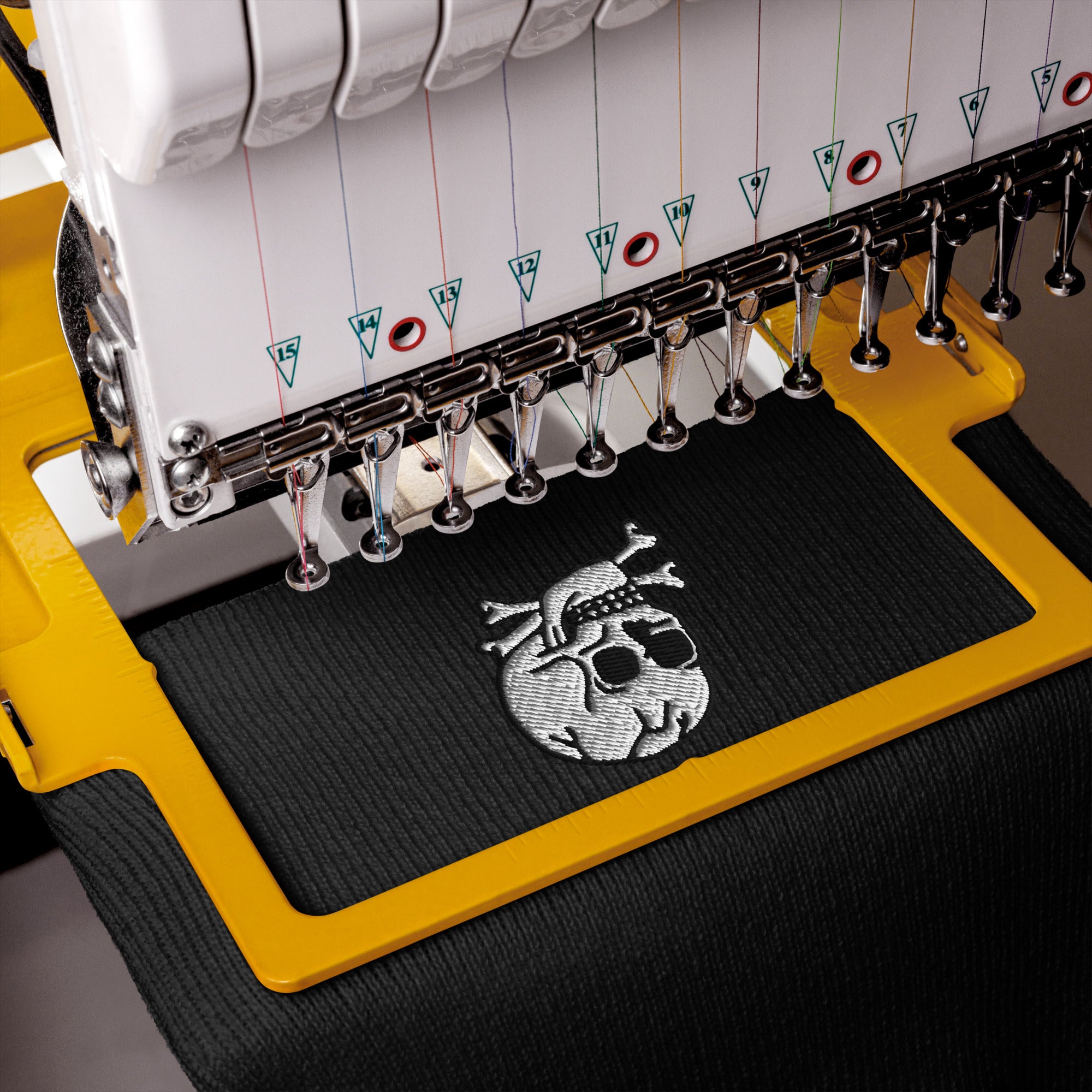 Embroidery machine with a skull design on a black fabric mat